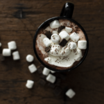 aerial view of hot cocoa on a dark brown wood background with marshmallows