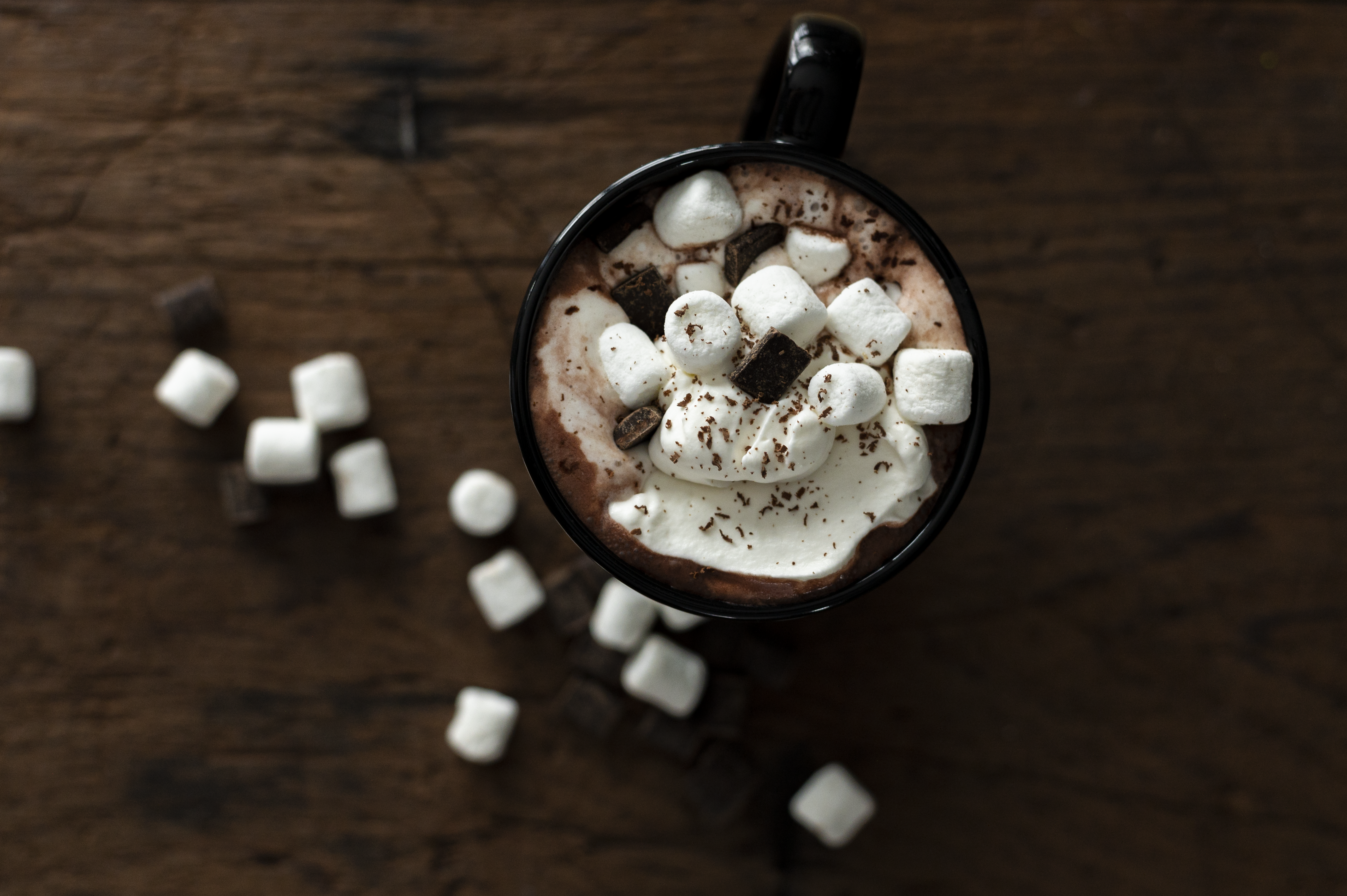 aerial view of hot cocoa on a dark brown wood background with marshmallows