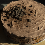 chocolate frosted icebox cake on a wood background with chocolate decoration and shavings