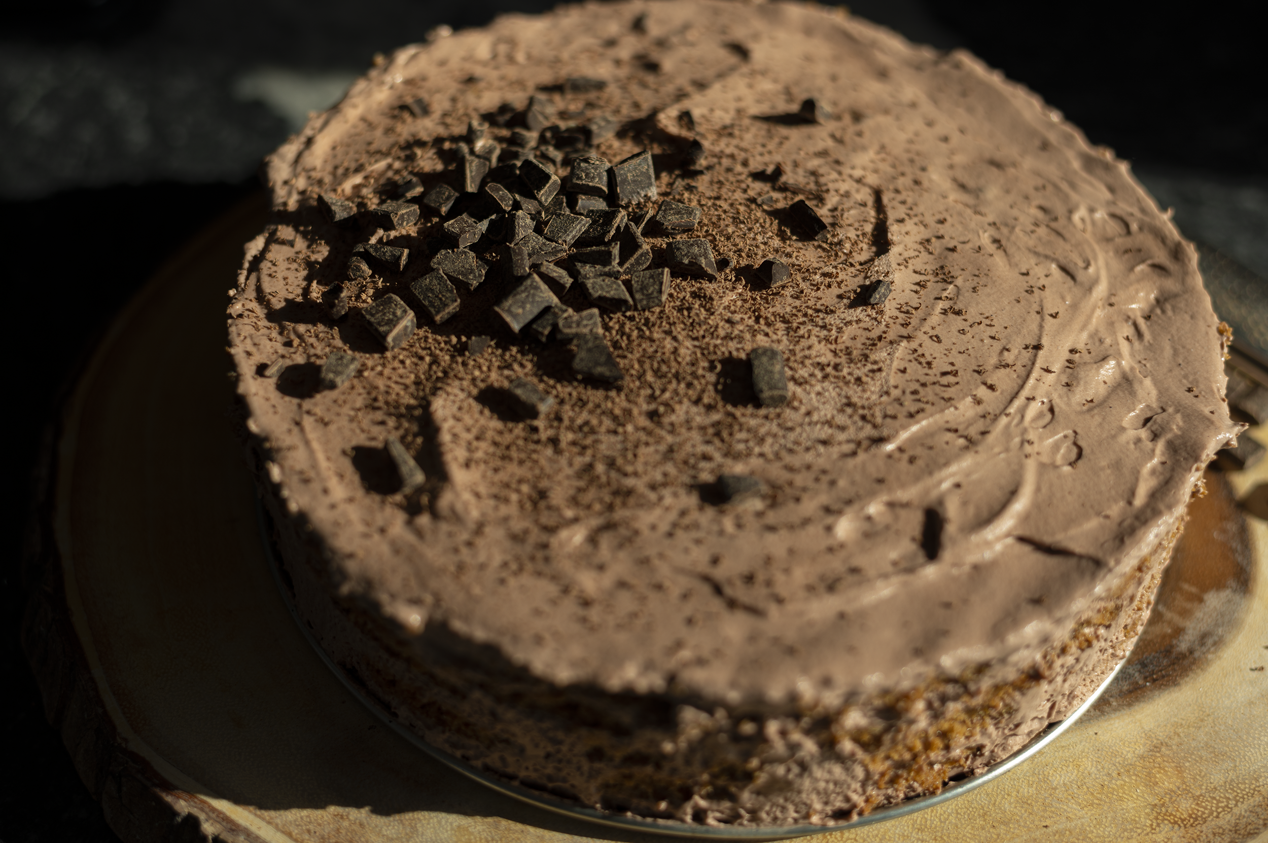 chocolate frosted icebox cake on a wood background with chocolate decoration and shavings